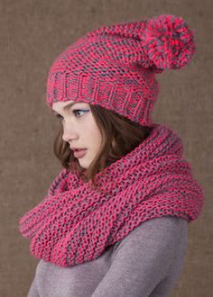 a woman wearing a pink knitted hat and scarf with pom - pom