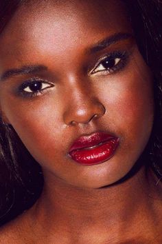 a close up of a woman with red lipstick on her face and dark hair, looking at the camera