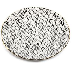 a white and gold plate with black dots on the rim, against a white background