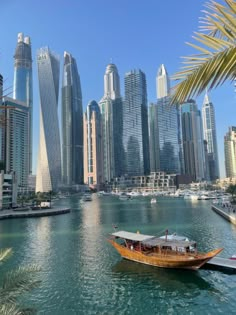 a boat is floating in the water near some tall buildings and palm tree's