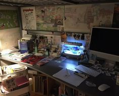 a cluttered desk with a computer monitor and keyboard on it, surrounded by other items