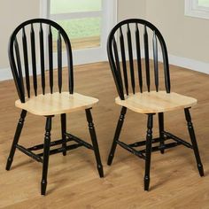 two wooden chairs sitting on top of a hard wood floor next to each other in front of a window