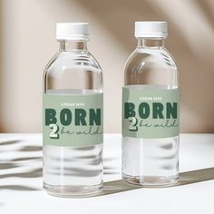 two bottled water bottles sitting on top of a white table next to each other with labels reading born 2 the wild