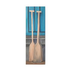 two wooden paddles sitting next to each other in front of a blue wall and window