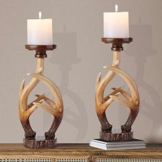 two candle holders made out of antler wood with white candles on top of them