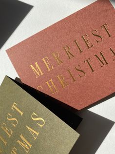 two red and gold christmas cards sitting on top of each other