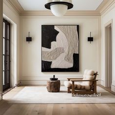 a large painting hangs on the wall above a chair and ottoman in an elegant living room