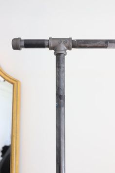 an old metal pipe is standing in front of a mirror on a table next to a wall