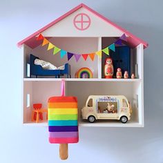 a toy house with ice cream and toys on the shelf above it, including a rainbow popsicle