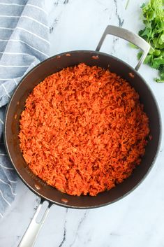 carrots in a frying pan on a marble counter top next to parsley