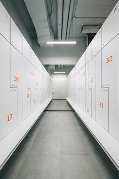 an empty hallway with white lockers and orange numbers