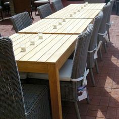 a wooden table sitting on top of a patio next to wicker chairs and tables