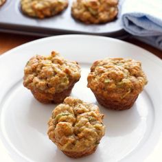 four muffins on a white plate next to a baking pan