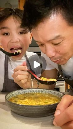 a father and son eating macaroni and cheese with spoons in their hands