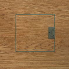 a wooden surface with a metal square in the middle and a light switch on it