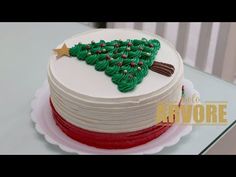 a white cake with green frosting and a red stripe around the bottom that has a christmas tree on it