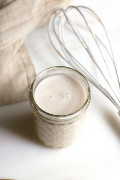 a whisk in a glass jar next to an egg beater