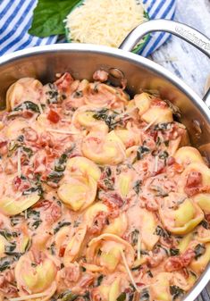 a pot filled with pasta and sauce on top of a wooden table next to a blue towel