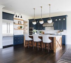 a kitchen with dark blue cabinets and white counter tops, wooden flooring and bar stools