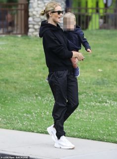 a woman holding a baby in her arms while walking down the street with another person