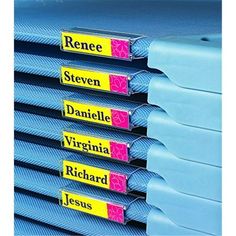 a stack of blue binders with yellow labels on each one side and pink tags on the other