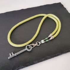 a yellow lanyard with a silver key on it and a green beaded cord