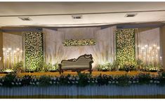 a couch sitting on top of a stage covered in flowers and greenery next to candles