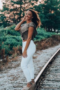 a woman standing on train tracks in white pants