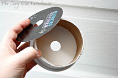 someone is holding a cd in front of a white door and opening it with their thumb