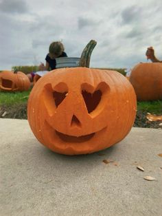 two pumpkins with faces carved into them sitting on the ground in front of some people