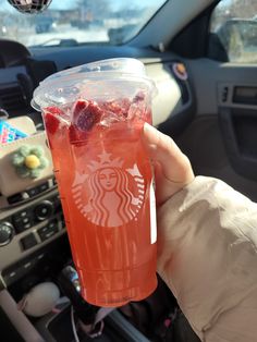 a person holding up a drink in their hand with strawberries on the inside of it