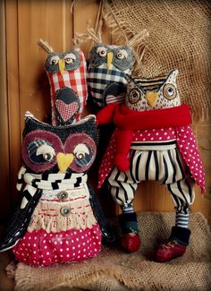 three stuffed owls sitting next to each other on top of a burlwood table