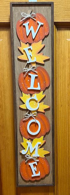 a wooden sign that says welcome with pumpkins