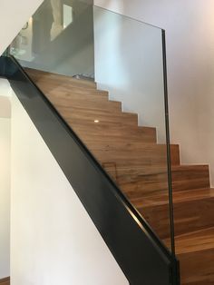 a stair case with glass railing and wooden handrail