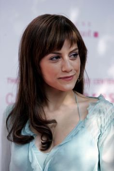 a woman with long brown hair and blue eyes