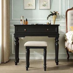 a black vanity table with a stool in front of it and pictures on the wall