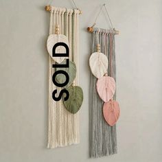 two wall hangings with the word sold written on one side and three different colored leaves attached to each other