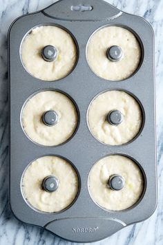 four donuts in a muffin tin on a marble counter