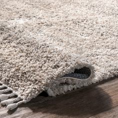 a close up of a rug on the floor with a wooden floor in the background