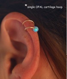 an ear with a single opal cartilage hoop attached to the side of it