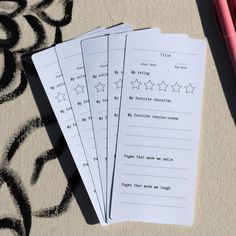 three notebooks sitting on top of a table next to a pen and paper with writing