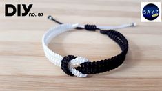 two black and white bracelets with one knot on the end, sitting on top of a wooden table