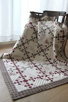 a chair with a quilt on it next to a window