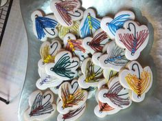 many decorated cookies are sitting on a silver platter and have colorful designs in the shape of fish