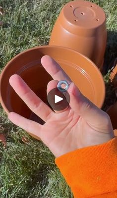 a person is holding a clay pot in their hand while standing on the grass outside