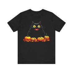 Embrace the spirit of Halloween with this playful black t-shirt featuring a whimsical design of a cheerful black cat surrounded by festive pumpkins. The vibrant colors and intricate details bring a fun and spooky vibe, making it a perfect addition to your seasonal wardrobe. Why You'll Love It: 👕 Ultimate Comfort: Made with 100% Airlume combed and ring-spun cotton, this tee offers a lightweight (4.2 oz/yd² or 142 g/m²) and breathable fabric that’s perfect for both active and leisure wear. 👔 Ver Halloween Cat Print Graphic Tee, Spooky Black T-shirt With Cat Design, Spooky Halloween T-shirt With Cat Design, Halloween Black T-shirt With Cat Design, White Cat Print T-shirt For Halloween, Black Halloween T-shirt With Cat Design, Spooky Black T-shirt With Cat Print, Cheap Black T-shirt With Cat Print, Halloween Cat Print Crew Neck T-shirt