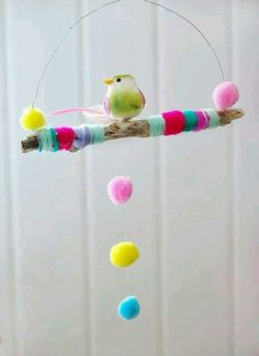 a bird is sitting on a branch with balls hanging from it