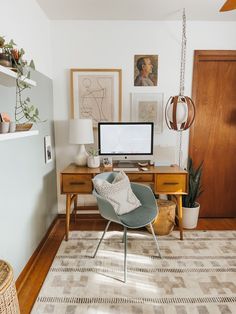 a living room with a computer on a desk next to a chair and potted plants