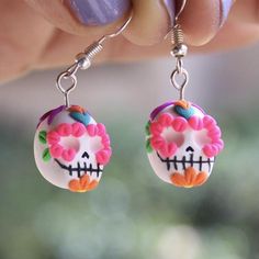 a pair of earrings with pink and orange sugar skull decorations hanging from it's ear wires