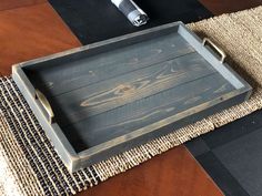 a wooden tray sitting on top of a rug next to a bottle of wine and a lighter